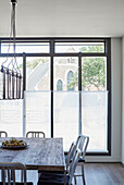 Backlit dining table and chairs at window of Rye barn conversion, East Sussex