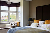 Yellow velvet cushions and bay window with view to sea from Northumbrian bedroom, UK