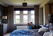 Ungemachtes Bett mit Blick auf das Meer in einem Haus in Northumbria, UK