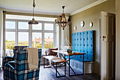 Große geknöpfte Sitzbank mit karierten Sesseln und Blick auf das Meer in einem Haus in Northumbria, UK