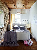 Papierschirme über einem Doppelbett mit freiliegender Steinwand in einem bretonischen Landhaus in Frankreich