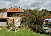 Garten mit Majestic-Bus neben einer holländischen Scheune in der Nähe von Hay-on-Wye, Wales, UK