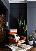 Vintage leather armchair and cacti with cut logs in Ramsgate living room Kent, UK
