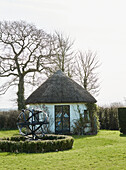 Reetgedecktes Sommerhaus und Gartenlaube auf dem Grundstück eines Hauses in Devon, UK