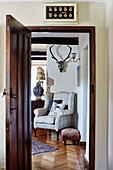 Upholstered armchair and parquet floor viewed through doorframe in Devon home, UK