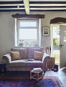 Zweisitzer-Sofa unter einem Fenster in einem renovierten Bauernhaus in Yorkshire, UK