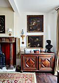 Framed artwork above carved wooden sideboard at fireside in Foix townhouse Ariege, France