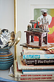 Chef figurine on recipe books with silver spoons in ceramic jug in Northern kitchen, UK