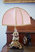 Rosa Vintage-Lampe mit Figur auf antikem Schreibtisch in einem Haus im Norden, UK