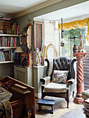 Grauer Sessel mit Knöpfen und Sockel mit Bücherregalen in einem Haus in Somerset, UK