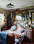 Antikes Bett mit verschiedenen Stoffen und Spiegel in einem Haus in Somerset, UK