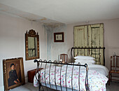 Gilt framed mirror and artwork with metal framed bed and salvaged doors in North Yorkshire farmhouse, UK
