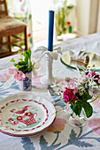Teller mit Schnittblumen und Kerze auf einem Tisch in einem Bauernhaus in Oxfordshire, UK
