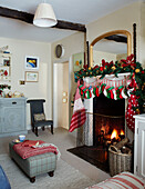 Lit fire with Christmas stockings mirror and footstool in British home