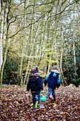 Zwei Jungen laufen durch herbstliches Laub im Wald