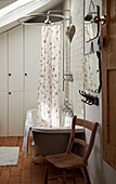 Floral shower curtain and vintage mirrors with chair in tiled bathroom of Brighton home East Sussex, England, UK