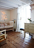 Fairylights above childs cot in bedroom with wooden floorboards and lace curtains in Brighton home East Sussex, England, UK