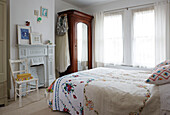 Embroidered bed cover and net curtains with mirrored wardrobe in Colchester family home, Essex, England, UK