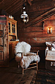 Armchair draped with sheepskin in corner of living room inside a Wooden cabin situated in the mountains of Sirdal, Norway