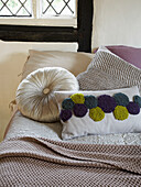 Verschiedene Kissen auf einem Bett mit Decke in einem Cottage in Herefordshire, England, UK
