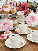 Cups and saucers with pink cupcakes in Winchester home, Hampshire, UK