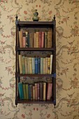 Bücherregal auf einer Tapete mit floralem Muster