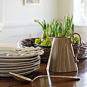 Stack of plates, jug and spring flowers on a table