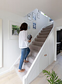 Frau auf der mit Teppich ausgelegten Treppe in einem Haus in Reigate, Surrey, UK