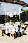 Solar lanterns above table with wooden seating and cushion fabrics in Colchester terrace, Essex, UK