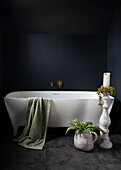 Vintage-Steinzeug setzt im Badezimmer einen markanten Akzent und kontrastiert mit der modernen Badewanne vor den dunklen Wänden