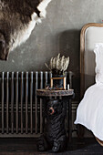 Antique side table in shape of bear with radiator at bedside in Somerset home UK