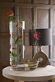 Tischplatte mit frischen Blumen, Lampe und Vase in einem holzgetäfelten Wohnzimmer aus der Zeit
