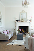 Beleuchtetes Feuer und Sofa mit Reisetruhe im Wohnzimmer eines Hauses in Canterbury, England UK