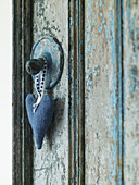 Blaues Liebesherz hängt an einem Lichtschalter mit gealterter Farbe in einem Bauernhaus in Gloucestershire, England, UK