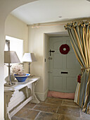 Matching lamps on console in flagstone entrance of Gloucestershire farmhouse, England, UK