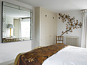 Built-in wardrobe and oversized mirror in bedroom reflecting light city of Bath home Somerset, England, UK