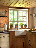 Sunlit window above belfast sink in converted Shropshire chapel kitchen England, UK