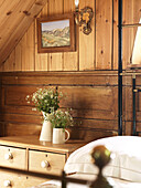 Cut flowers on chest of drawers in bedroom of Shropshire chapel conversion England, UK