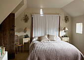 Kopfteil aus weißem Stoff auf einem Bett in einem Haus in Gloucestershire, England, UK