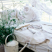 Vintage-Liege im Gartenhaus mit geblümter Bettwäsche