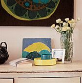 Detail of painted white vintage sideboard with green and blue ornaments painting and retro wall hanging
