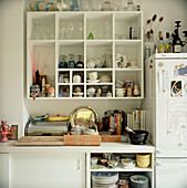 Open plan white kitchen units with crockery utensils glassware cook books and homeware on show