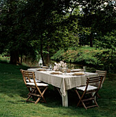 Garden party table setting in an idyllic place by a tree lined river in the summertime