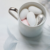 Cup of sugar coated almonds on a white tabletop