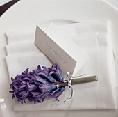 Detail of a white table setting with a name tag attached to a purple hyacinth