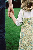 Rear view of young girl holding mothers hand