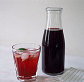 Glass bottle and glass full of blackcurrant juice 