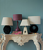 Ornate painted console table with collection of table lamps