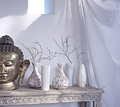 Ornate console table displaying ceramic vases home wares and a metallic Buda head