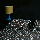 Doppelbett mit gemusterter Bettwäsche und dunkel gestrichenen Wänden